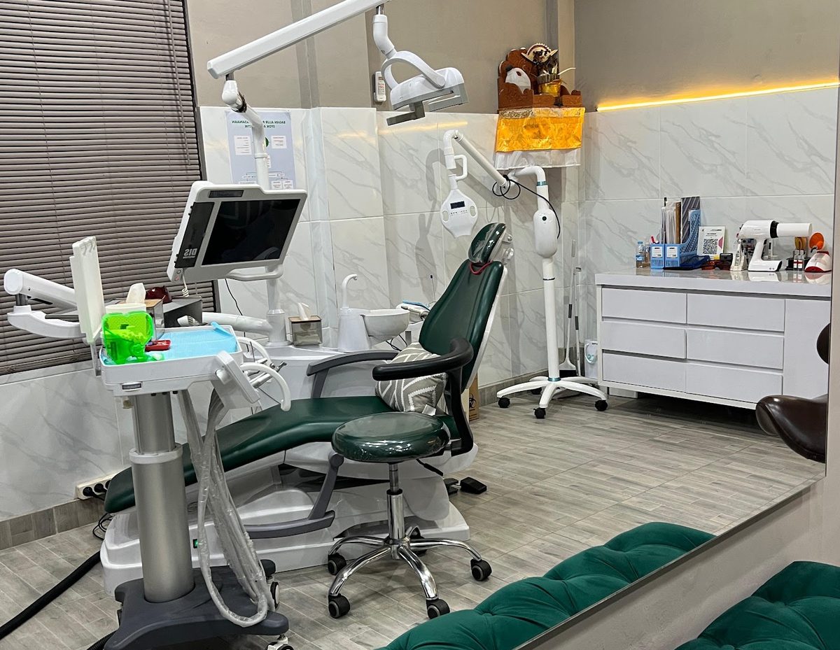 A treatment room at MSDC Bali Dental Care, with a green dental chair and marble walls
